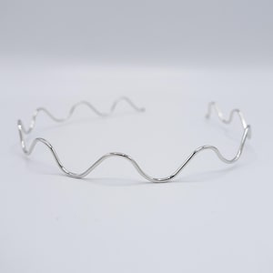May include: A silver wavy headband made of thin metal wire.