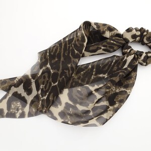 May include: A brown and beige leopard print hair scrunchie with a long, flowing tail.