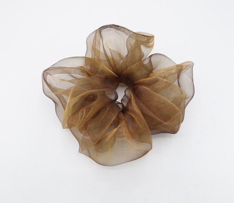 May include: A brown sheer fabric hair scrunchie. The scrunchie is made of a soft, delicate material and is designed to be gentle on hair.