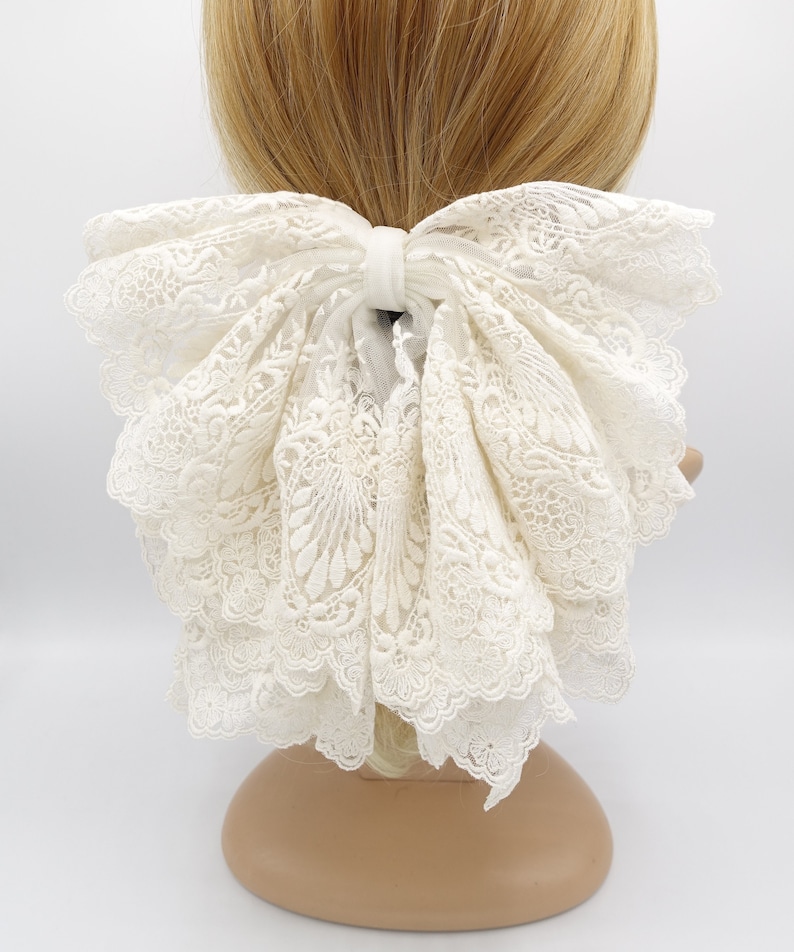 May include: A large white lace bow hair tie. The bow is made of delicate white lace and is tied in a large, full bow.