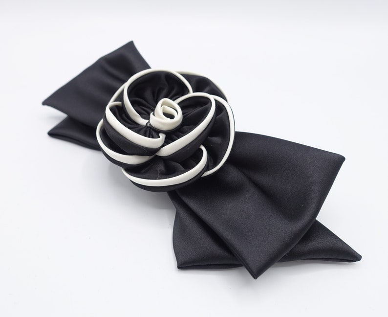May include: A black satin bow with a white and black fabric rose.