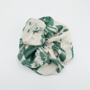 May include: A green and white patterned scrunchie made of satin fabric.