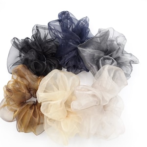 May include: A set of six hair scrunchies in various shades of brown, black, and beige. The scrunchies are made of a soft, sheer fabric and are perfect for adding a touch of elegance to any hairstyle.