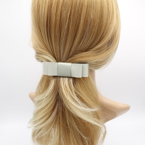 May include: A light grey satin bow hair clip. The bow is tied in a simple knot and has a smooth, shiny finish.