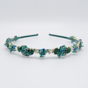 May include: A gold headband with a row of emerald green and clear crystal rhinestones.