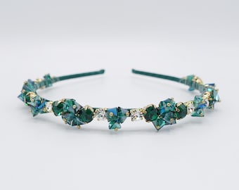 May include: A gold headband with a row of emerald green and clear crystal rhinestones.