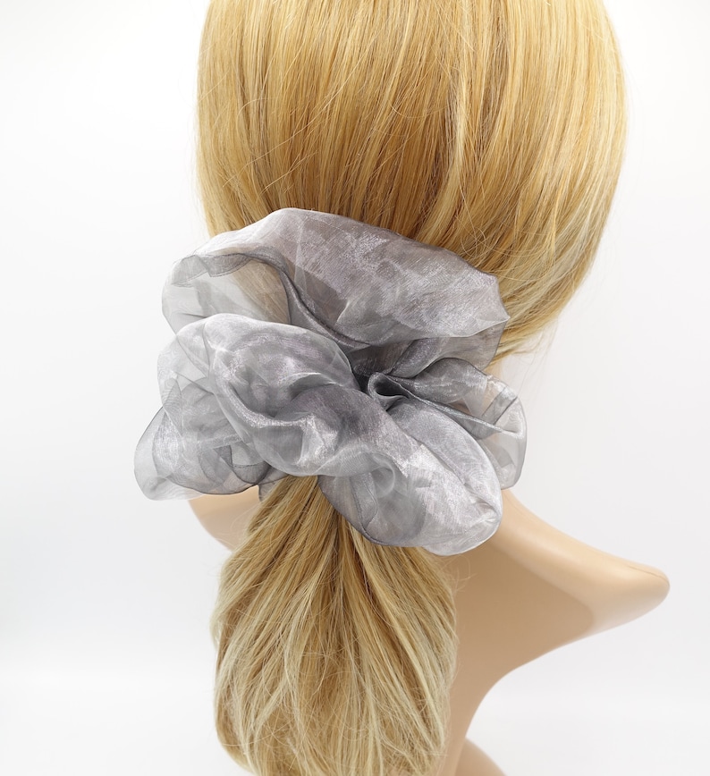 May include: A gray, sheer, large scrunchie made of fabric. The scrunchie is tied around a ponytail.