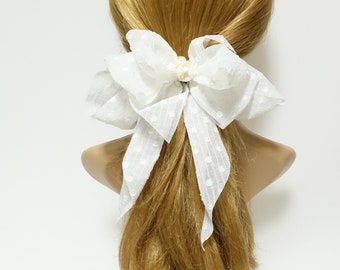 May include: White polka dot hair bow with a pearl accent. The bow is tied in a large, loose knot and is made of a soft, sheer fabric.