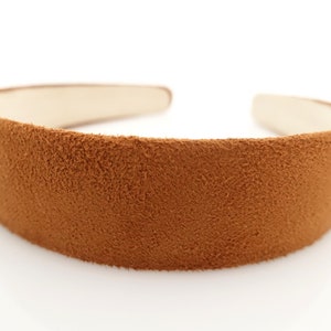 Puede incluir: Una diadema de ante marrón con una banda ancha y cómoda.