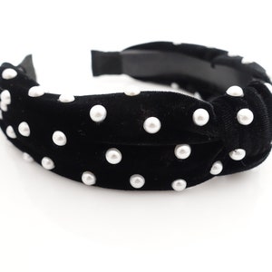 May include: Black velvet headband with a knotted design and white pearl embellishments.