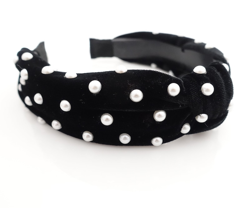 May include: Black velvet headband with a knotted design and white pearl embellishments.