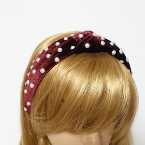 May include: A burgundy velvet headband with a knotted design and white pearl embellishments.