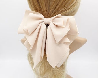 May include: A large, pale pink bow made of soft fabric. The bow is tied with a simple knot and has a layered, ruffled design.