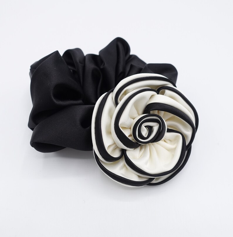 May include: A black satin scrunchie with a large white and black fabric flower.