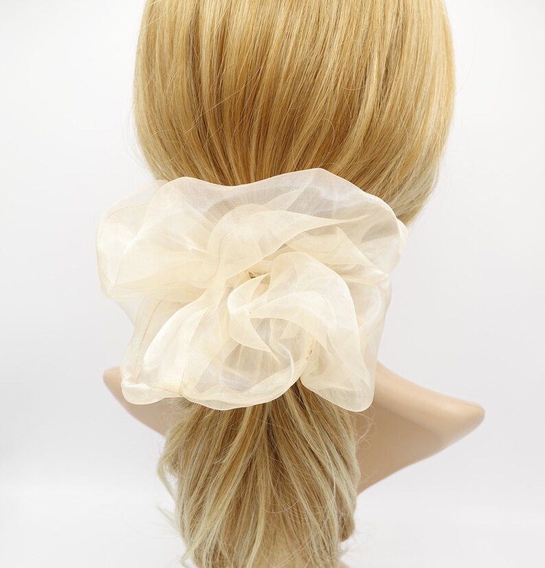 May include: A large, ivory-colored,  fluffy hair scrunchie made of sheer fabric.
