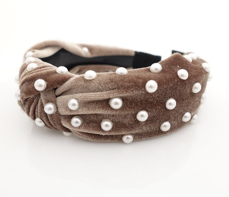 May include: A brown velvet headband with a knotted design and white pearl embellishments.
