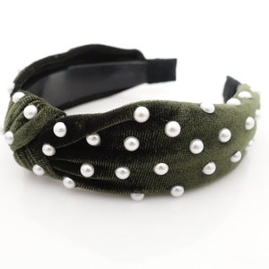 May include: A dark green velvet headband with white pearl embellishments. The headband is knotted on top and has a simple elastic band.