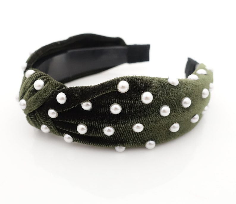 May include: A dark green velvet headband with white pearl embellishments. The headband is knotted on top and has a simple elastic band.