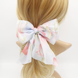Könnte beinhalten: Ein hellblaues Haarbändchen mit einem Blumendruck mit rosa Blüten und grünen Blättern.