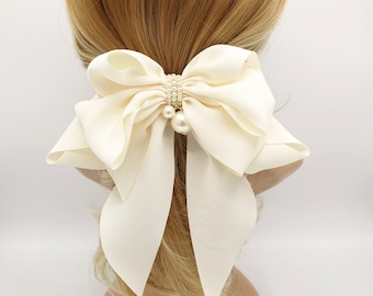 May include: A large ivory satin bow hair tie with a pearl and rhinestone embellishment.