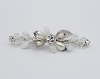 May include: A silver hair clip with white pearls, clear crystals, and a silver leaf design.
