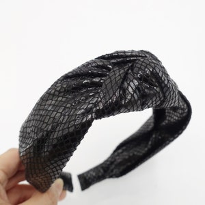 Op de afbeelding: Zwarte geknoopte hoofdband met een slangenhuidpatroon.
