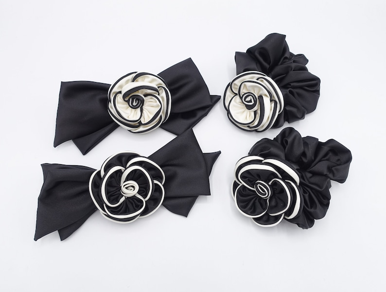 May include: Four black satin hair scrunchies with white and black fabric flower accents.