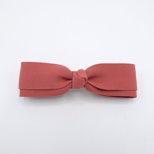 May include: A terracotta-coloured fabric bow tie. The bow is tied in a simple knot.
