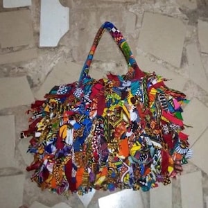 May include: A colorful tote bag made from scraps of fabric. The bag has a fringed design and is made in a variety of bright colors, including red, yellow, blue, and green.