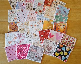 May include: A collection of square cards with various designs, including hearts, floral patterns, birds, and the word "Love". The cards feature a mix of colors, such as red, pink, blue, and yellow, and are arranged on a wooden surface.