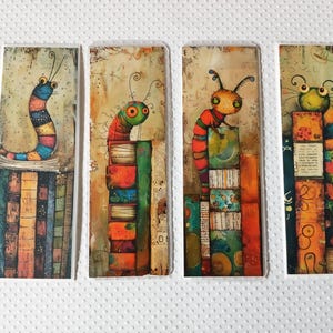 May include: Four whimsical bookmarks featuring colorful, cartoonish caterpillars perched on stacks of books. Each bookmark has a unique design with vibrant hues of blue, orange, green, and red. The illustrations have a textured, artistic style.