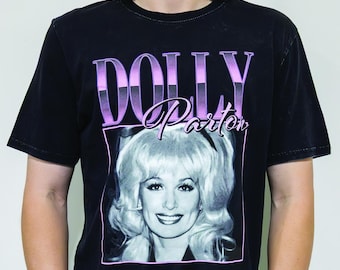 May include: Black t-shirt with a vintage-style graphic of Dolly Parton. The graphic features a black and white photo of Dolly Parton with the text "DOLLY Parton" in pink and purple.