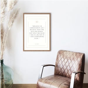 Puede incluir: Un cuadro enmarcado con una cita de C.S. Lewis sobre un fondo blanco. La cita dice: «Creo en el cristianismo como creo que el sol ha salido: no solo porque lo veo, sino porque a través de él veo todo lo demás». El marco es de color marrón claro.