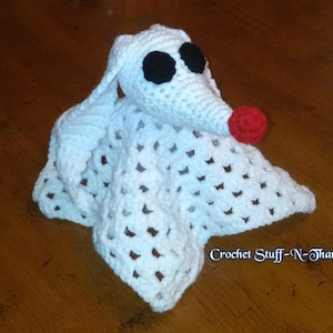 May include: White crocheted blanket with a ghost-like character attached. The character has black eyes and a red nose. The blanket has a crocheted pattern and the text "Crochet Stuff-N-Thangs" is visible in the bottom right corner.
