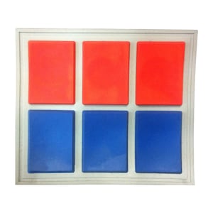 May include: A geometric wall art piece with six rectangular blocks. The top three blocks are bright red, and the bottom three are blue. The blocks are set within a white, rectangular frame.