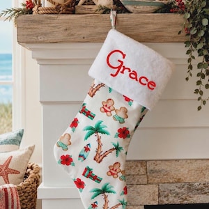 May include: A white Christmas stocking with a plush white cuff featuring the name Grace embroidered in red. The stocking is decorated with a repeating pattern of gingerbread people, palm trees, surfboards, and red hibiscus flowers.