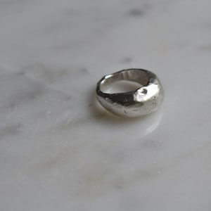 May include: A silver ring with a textured, rounded top.