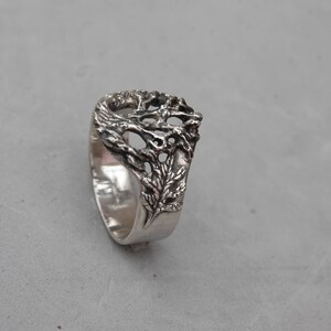 May include: A silver ring with a detailed tree design. The tree branches are intricate and delicate, creating a unique and eye-catching piece of jewelry.