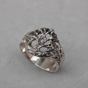 May include: A silver ring with a tree design. The tree is made of intricate branches and leaves.
