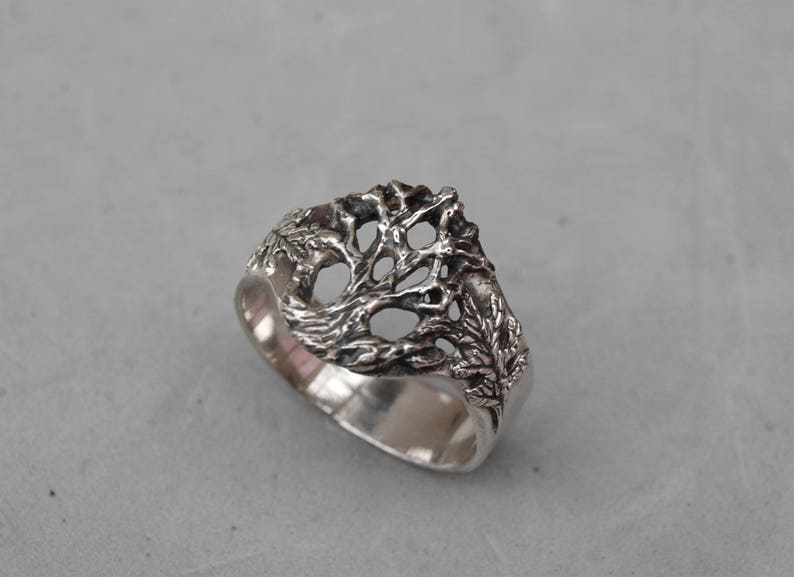 May include: A silver ring with a tree design. The tree is made of intricate branches and leaves.