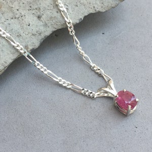 May include: A silver chain necklace with a pink gemstone pendant.