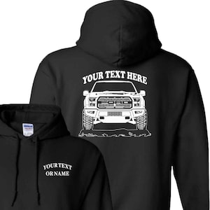 May include: Black hooded sweatshirt with a white outline of a Ford F-150 pickup truck on the back. The text "YOUR TEXT HERE" is above the truck. The front of the sweatshirt has the text "YOURTEXT ORNAME" in white.