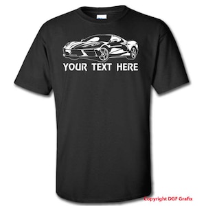 May include: Black t-shirt featuring a white graphic of a sports car. The car is depicted in a detailed line drawing style. Below the car is the text "YOUR TEXT HERE".