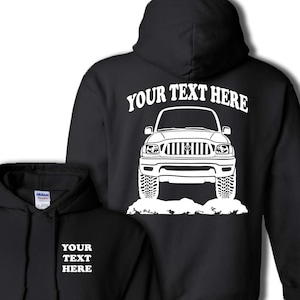 May include: Black hoodie with a white outline of a Toyota Tacoma truck on the back. The text "YOUR TEXT HERE" is above the truck. The front of the hoodie has the text "YOUR TEXT HERE" in white.