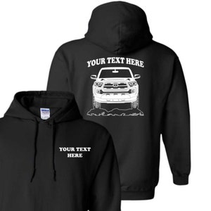 May include: Black hooded sweatshirt with a white outline of a Toyota Tacoma truck on the back and the text "YOUR TEXT HERE" above the truck. The front of the sweatshirt has the text "YOUR TEXT HERE" in white.
