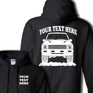 May include: Black hoodie with a white graphic of a vintage truck on the back. The text "YOUR TEXT HERE" is above the truck. The front of the hoodie has the text "YOUR TEXT HERE" in white.