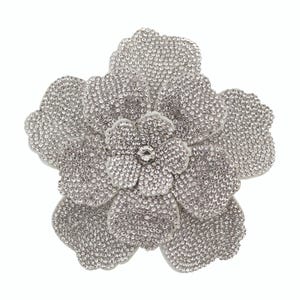 May include: A large, silver-toned flower brooch, heavily embellished with sparkling rhinestones. The brooch features multiple layers of petals, with a central, smaller flower also adorned with rhinestones. The design is set against a white background.