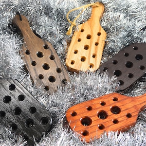 Puede incluir: Cuatro tapones de botella de madera con un diseño único que presenta una serie de agujeros. Los tapones son de varios tonos de marrón, negro y rojo.