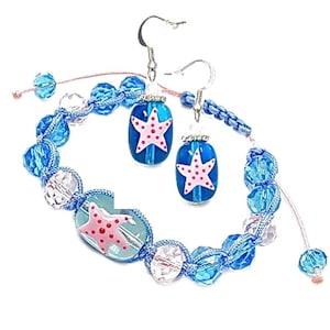 Puede incluir: Un conjunto de joyas a juego con una pulsera y pendientes. La pulsera y los pendientes tienen cuentas azules y un diseño de estrella de mar rosa. Los pendientes tienen ganchos plateados. La pulsera es ajustable.