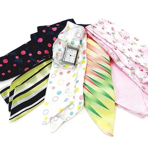 May include: A set of six colorful patterned silk scarves with a silver watch in the center. The scarves are in various patterns, including polka dots, stripes, and floral designs.